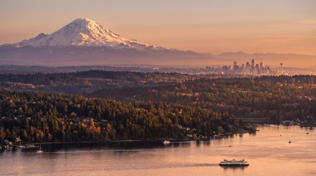 Mount Rainier and the Seattle skyline at sunset, with a ferry crossing Puget Sound